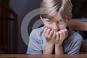 Frightened kid sitting at table