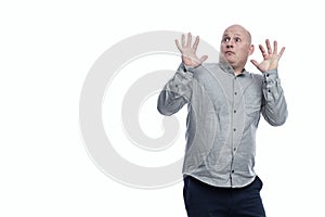 Frightened man with his hands raised up. A guy in a gray shirt and dark blue jeans. Full height. Isolated on a white background.