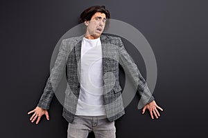 frightened man stand in shock, scared by something, leaned on black wall