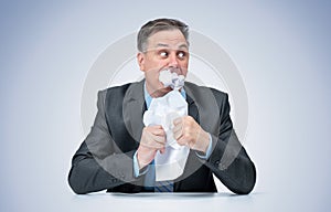 A frightened official in a dark suit eats the evidence paper, on a light blue background.
