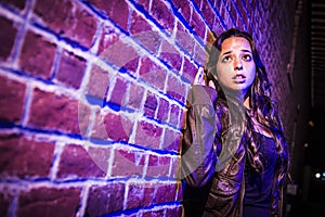 Frightened Pretty Young Woman Against Brick Wall at Night