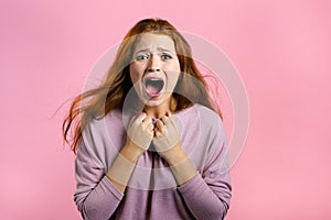 Frightened and screaming woman shocked isolated over pink background. Stressed and depressed pretty girl because of bad