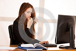 Frightened stressed woman working at her desk in the office, reading bad report.