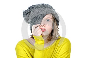 Frightened teen girl covers her face with a cap.