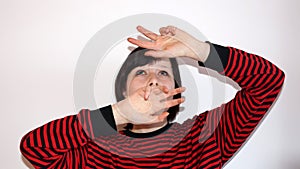 Frightened teenage girl covers her head with her hands on the white background