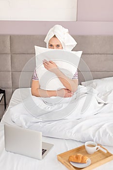 Frightened woman embracing the pillow as she is afraid of somebody