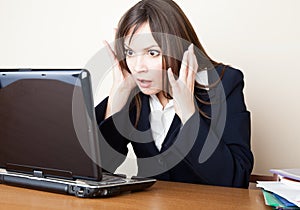 Frightened woman is looking at the laptop screen