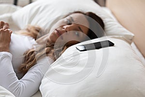 Frightened woman lying in bed looking on smartphone feels