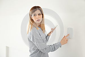 Frightened woman with tablet using security system indoors