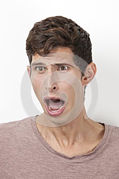 Frightened young man screaming against white background