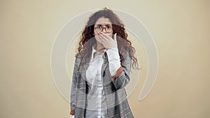 The frightened young woman with her hand to her mouth looks around in amazement.