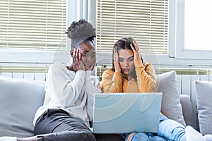 Frightened young women watching movie at home. Girls watching a terror movie on tv sitting on a couch at home. Girlfriends