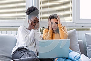 Frightened young women watching movie at home. Girls watching a terror movie on tv sitting on a couch at home. Girlfriends