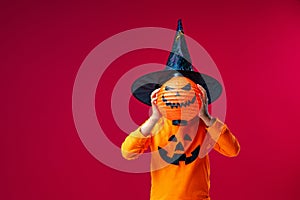 Frightening baby costume with pumpkin Jack instead head on green background