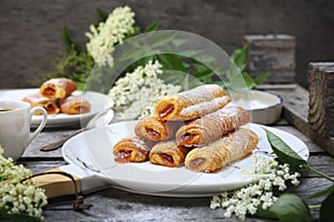 Fripons, French pastries. Apricot jam sweet puff pastry rolls and spring elderberry flowers