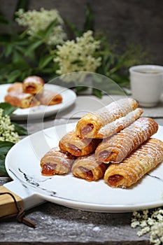 Fripons, French pastries. Jam filling sweet puff pastry rolls and spring elderberry flowers