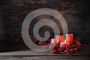 Frist Advent with red berry decoration and candles in a wreath, one is lighted, holiday home decor against a dark rustic wooden