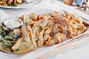 Frito misto fried seafood on a wooden tray in a restaurant