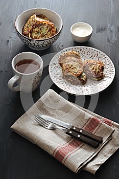 Fritters of zucchini with tea on rusticbackground