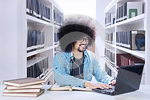 Frizzy student with laptop and earphone in library