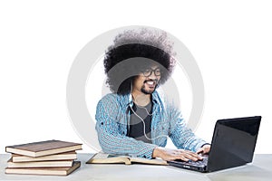 Frizzy student using a laptop and headset on studio