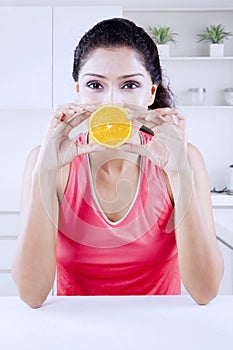 Frizzy woman covering her mouth with orange fruit