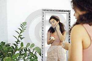 fro Girl Applying Eye Cream Looking In Mirror Standing In living room