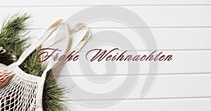 Frohe weihnachten text in red over shopping bag with christmas bracnhes on white wood background