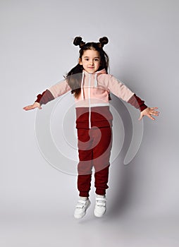 Frolic brunette kid girl in modern fashion pink brown sportwear is jumping having fun