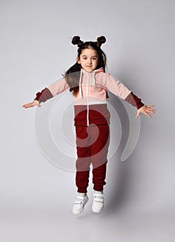Frolic brunette kid girl in modern fashion pink brown sportwear is jumping having fun photo