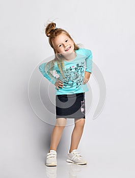 Frolic playful blonde kid girl in stylish shirt and denim skirt with cats kitties and sneakers has fun making faces