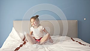 Frolicsome little girl having fun jumping on bed.