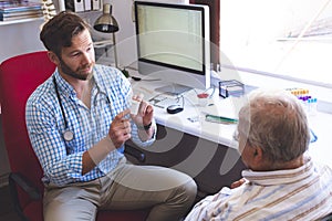 Male doctor prescribing pills to his senior male patient in clinic photo