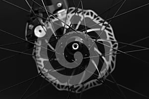 front bicycle wheel with braking disk and bike components on the black background