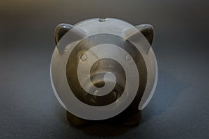 Front of the black piggy bank on the black background, the symbol of saving for a rainy day