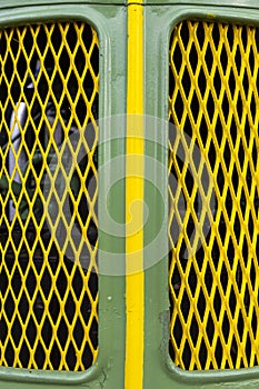 Front, bonnet, grille of a vintage tractor in green with yellow central stripe and yellow diamond-shaped air intake grille and