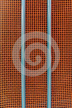 Front, bonnet, grille of a vintage tractor with red mesh air intake grille and two vertical struts in blue