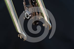 The front brake and the iron chrome-plated rigid bicycle fork are close-up on a black background. Professional bicycle workshop