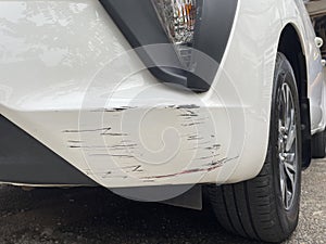 The front bumper of the white car tire was damaged by scratches