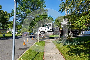 The front cab of a large white heavy duty truck with its front elevated wheels off of the ground by stabilizers