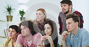 In front of the camera a big group of attractive people friends watching concentrated a movie or a sport match making a