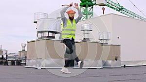 In front of the camera charismatic dancing engineer on the top of the building have moving very enthusiastic he wearing