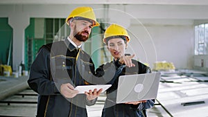 In front of the camera good looking woman engineer and her assistant walking through the large space building woman