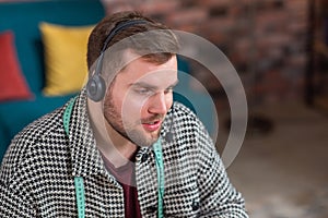 In front of the camera at tailoring atelier good looking man tailor speaks using the headphones with some customer he