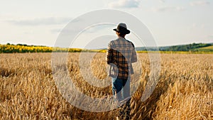In front of the camera taking video from the back walking to the large wheat field farmer man he enjoy the time and