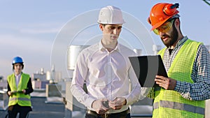 In front of the camera in the top of the construction building businessman have a discussing with the engineer about the