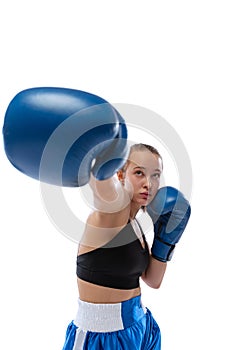 Front camera view of young girl, professional boxer practicing in sports uniform and boxing gloves isolated on white