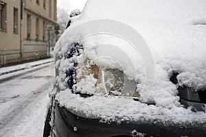 front car covered by the snow parked in the street by snowy day