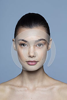 Front closeup portrait of a beauty brunette young woman with natural makeup, isolated grey background.