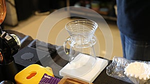 In front of the coffee bean grinder, there is a V60 pot and a teapot to collect coffee drops on a digital scale